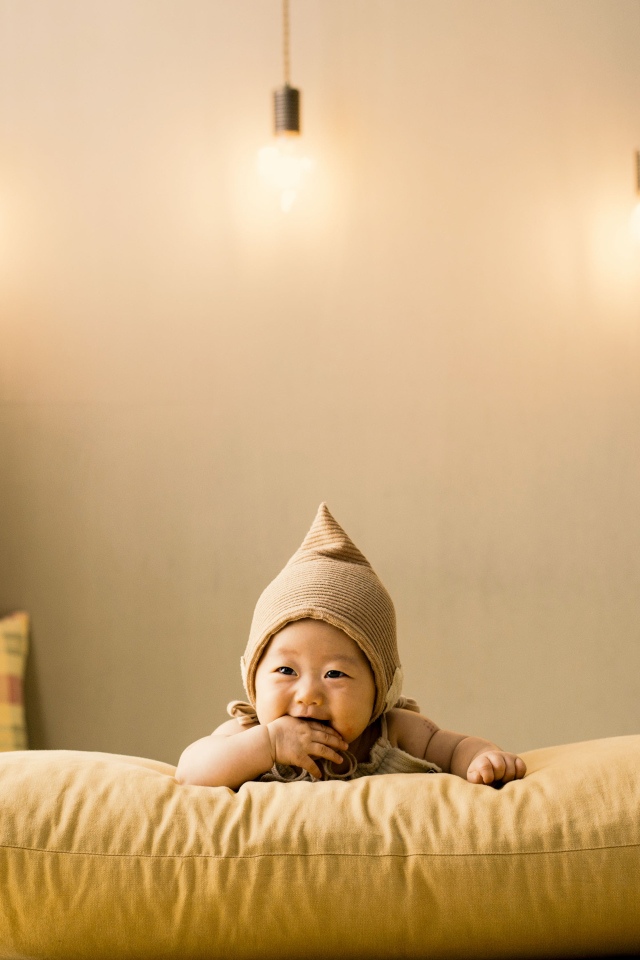 Маленький ребенок лежит на подушке под лампами