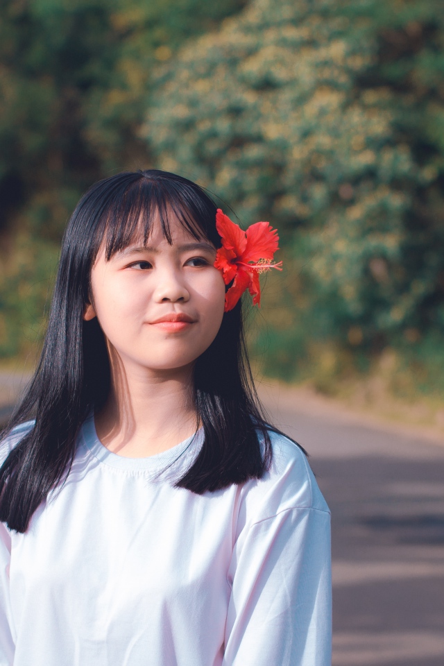 Девушка азиатка с красным цветком гибискуса в волосах