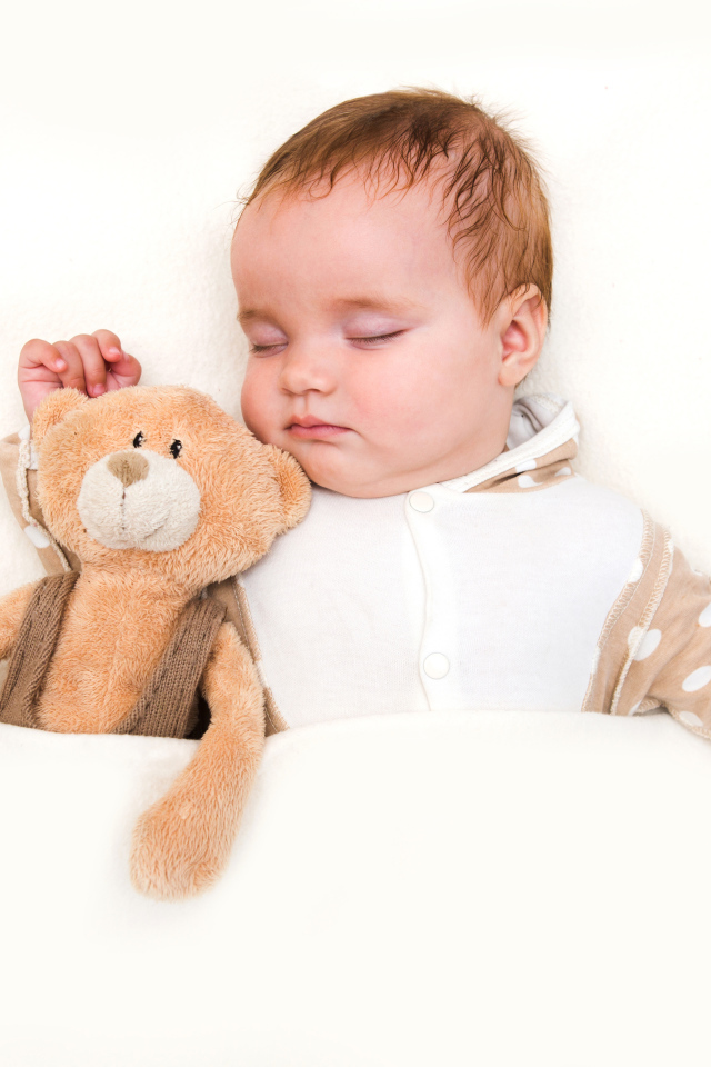 Грудной ребенок спит с плюшевым мишкой на белом фоне
