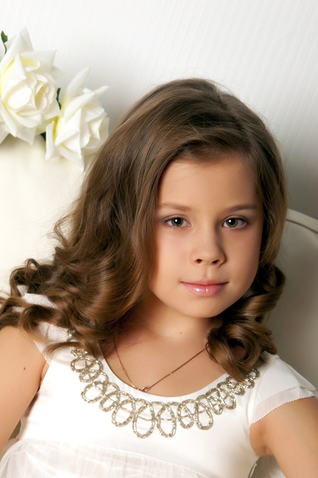 Красивая маленькая девочка сидит в кресле