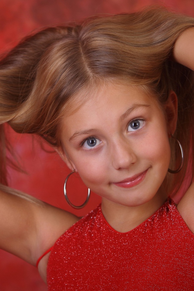 Красивая маленькая девочка с руками в волосах