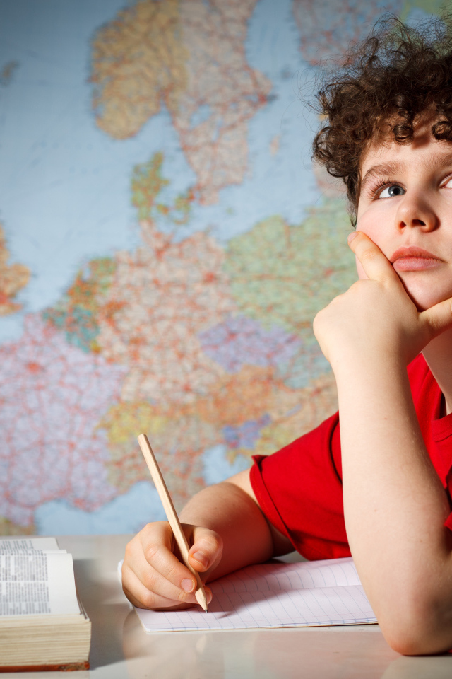 Мальчик ученик делает уроки за столом 