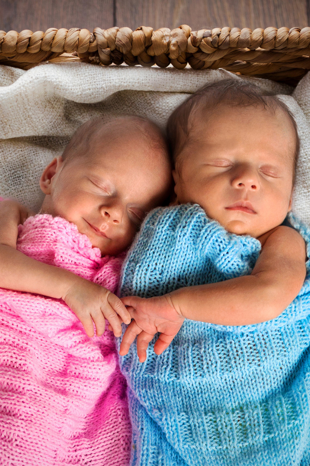 Грудные мальчик и девочка спят в плетеной корзине