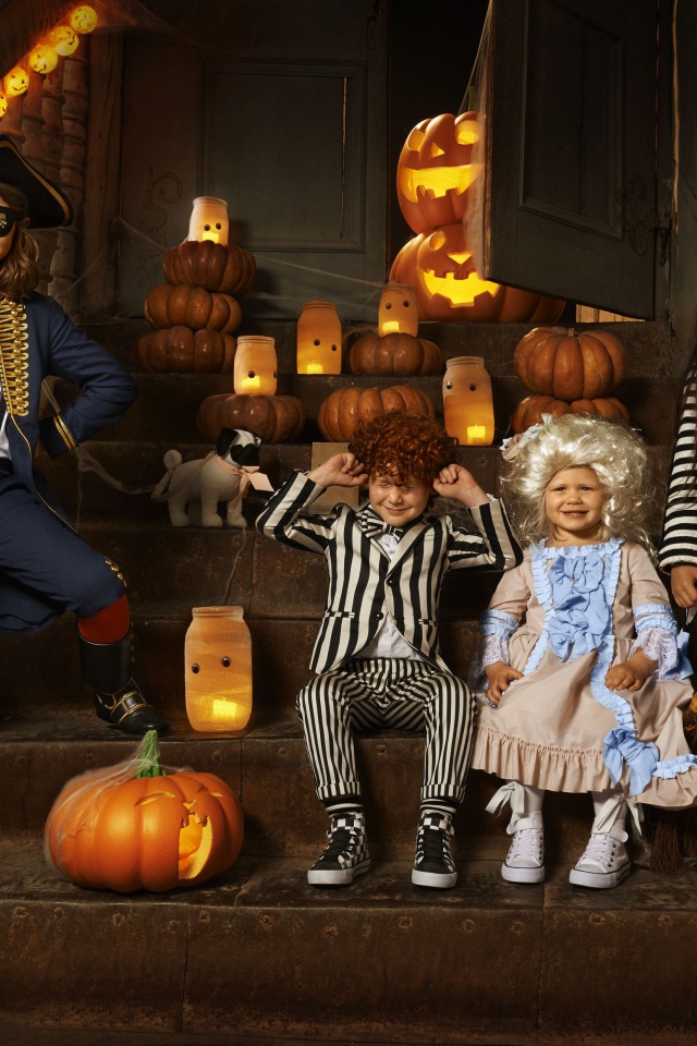 Дети в костюмах на Хэллоуин с тыквами на ступеньках