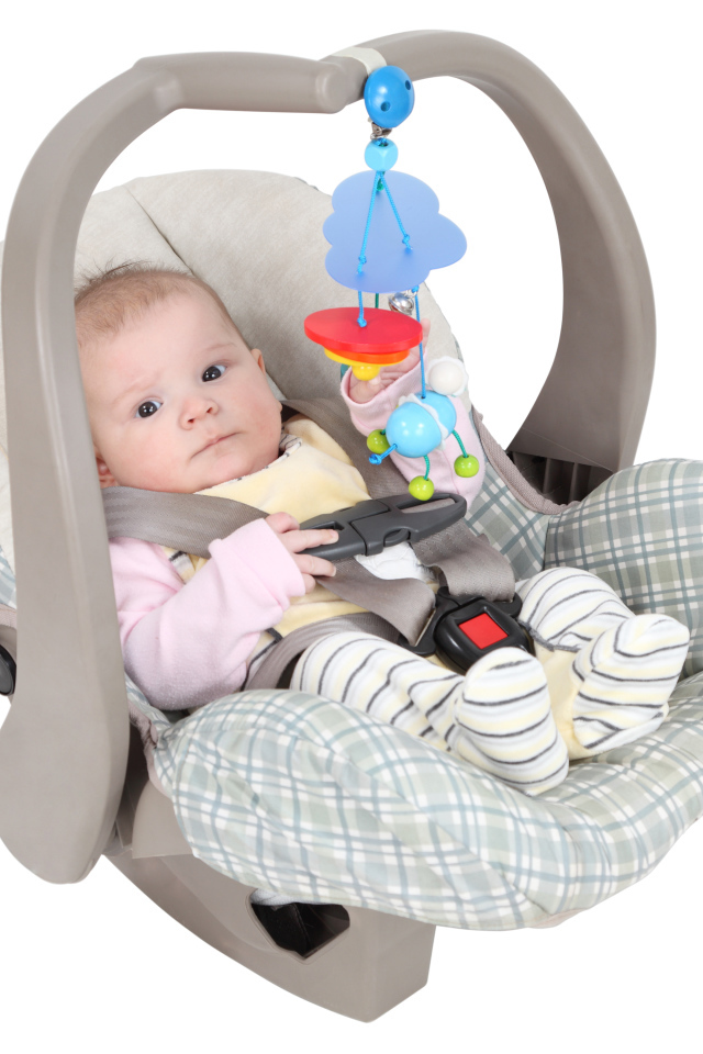 Маленький грудной ребенок в автомобильном кресле на белом фоне