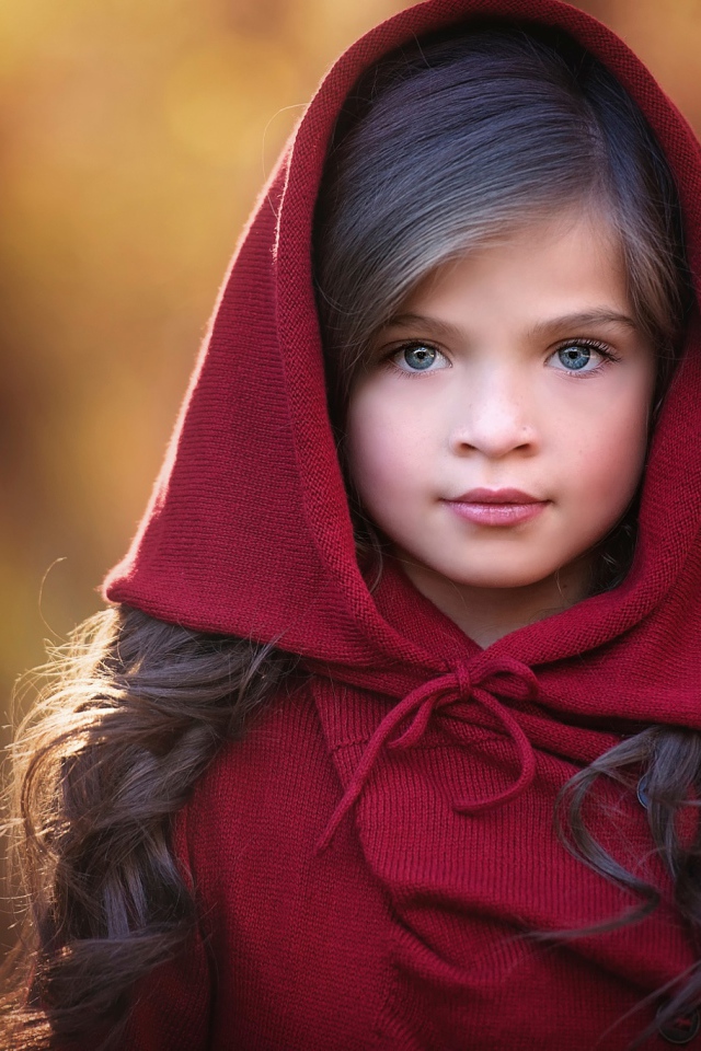 Маленькая красивая голубоглазая девочка с красным капюшоном на голове