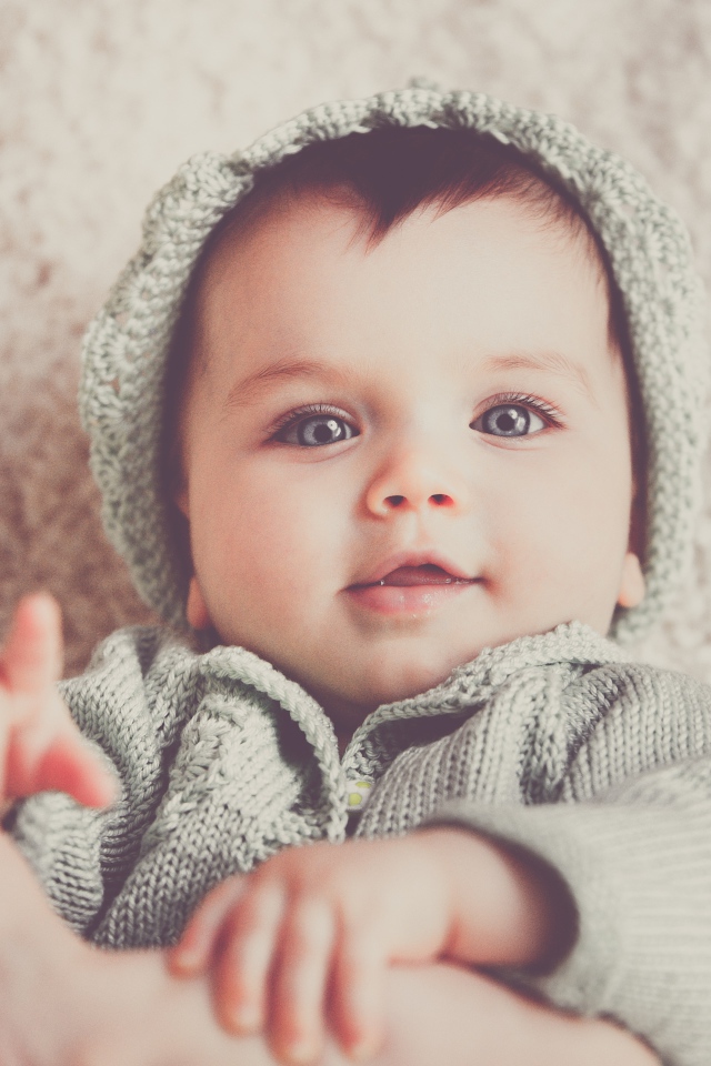Маленький голубоглазый улыбающийся ребенок в вязаном костюме