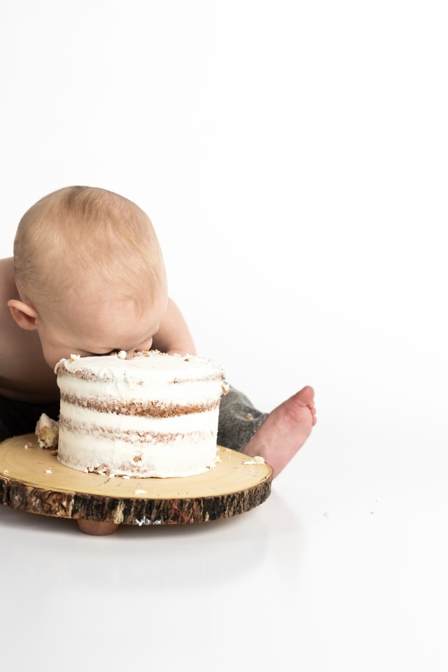 Маленький мальчик ест торт на белом фоне