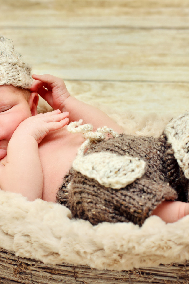 Маленький мальчик в вязаной шапке спит в корзине