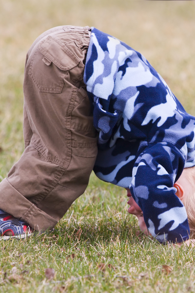 Маленький мальчик играет на траве с мячом