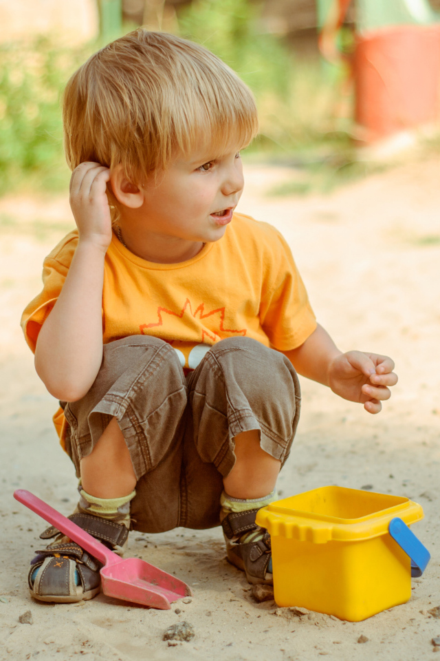 Маленький мальчик играет на песке 
