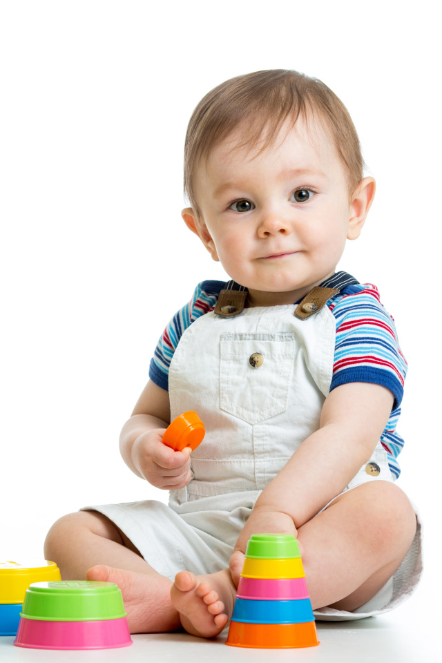 Маленький мальчик играет с пирамидкой на белом фоне