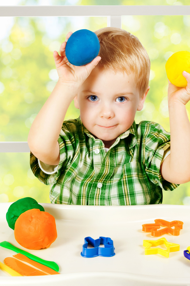 Маленький мальчик играет с игрушками у окна