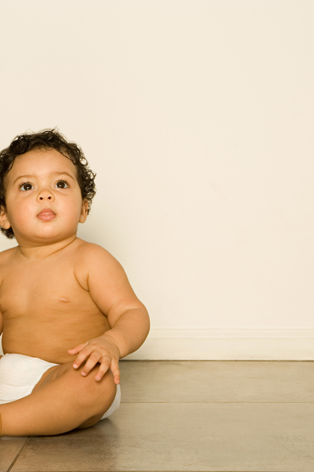 Маленький мальчик сидит на полу с игрушкой