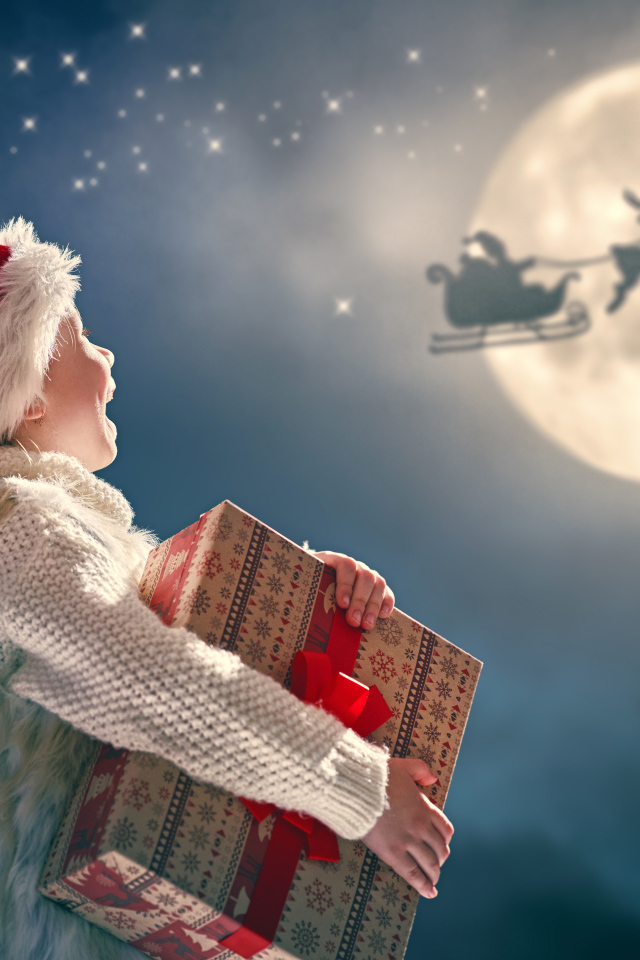 Маленький мальчик с подарком смотрит на улетающего Санта Клауса