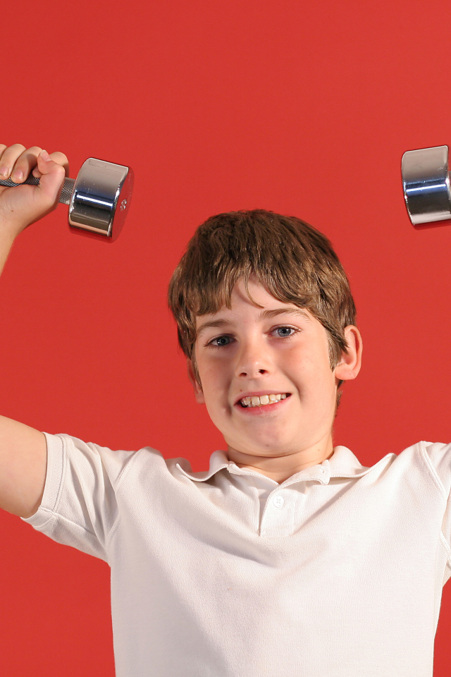 Маленький мальчик с гантелями на красном фоне