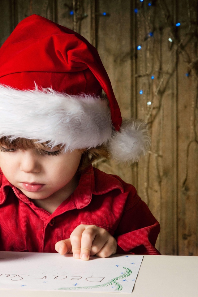 Маленький мальчик пишет письмо Деду Морозу 