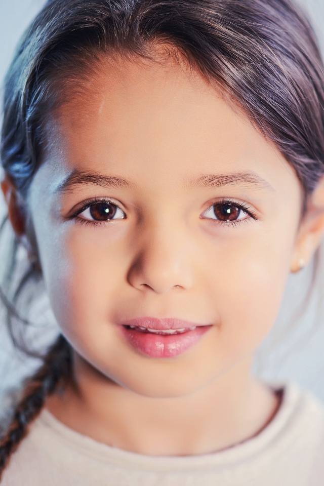 Маленькая кареглазая девочка на сером фоне