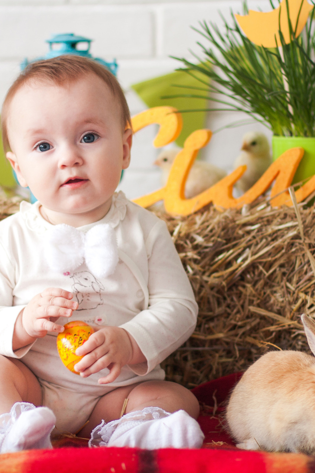 Маленький ребенок с крашеным яйцом и декоративным кроликом