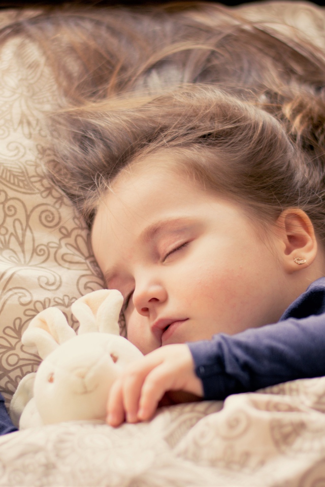 Маленькая милая спящая девочка с игрушкой под одеялом