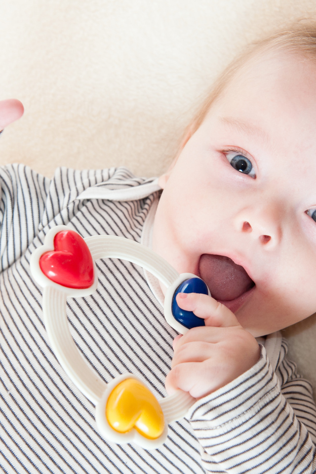 Маленький забавный голубоглазый ребенок с погремушкой
