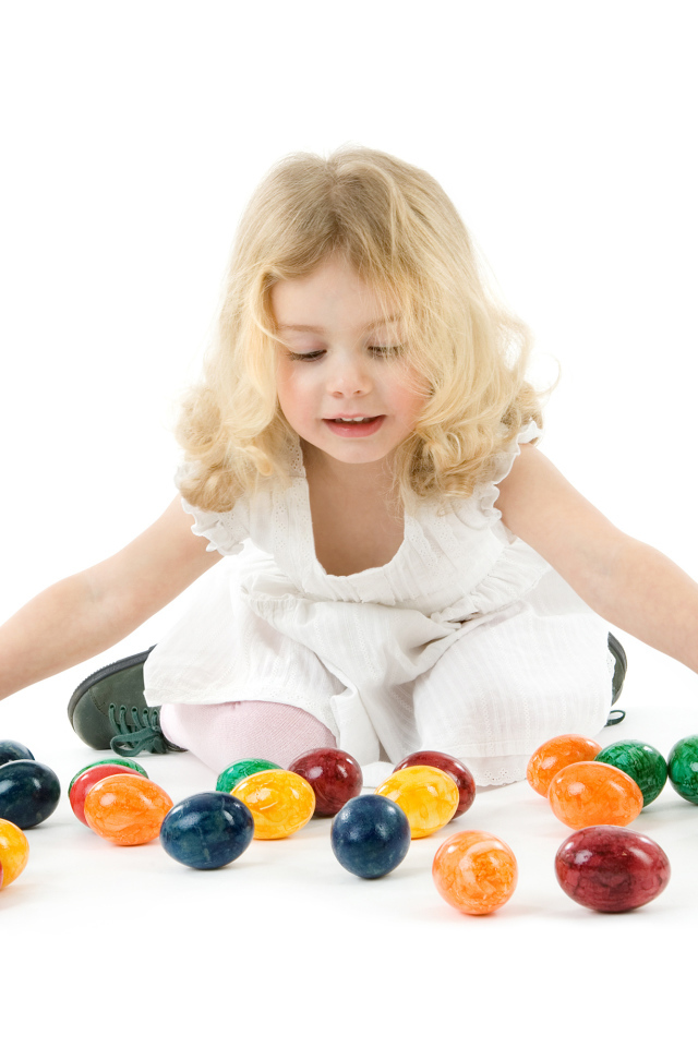 Маленькая девочка блондинка с крашеными яйцами на белом фоне