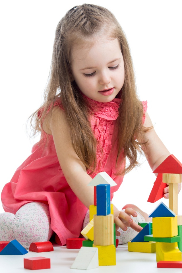 Маленькая девочка строит домик из кубиков на белом фоне