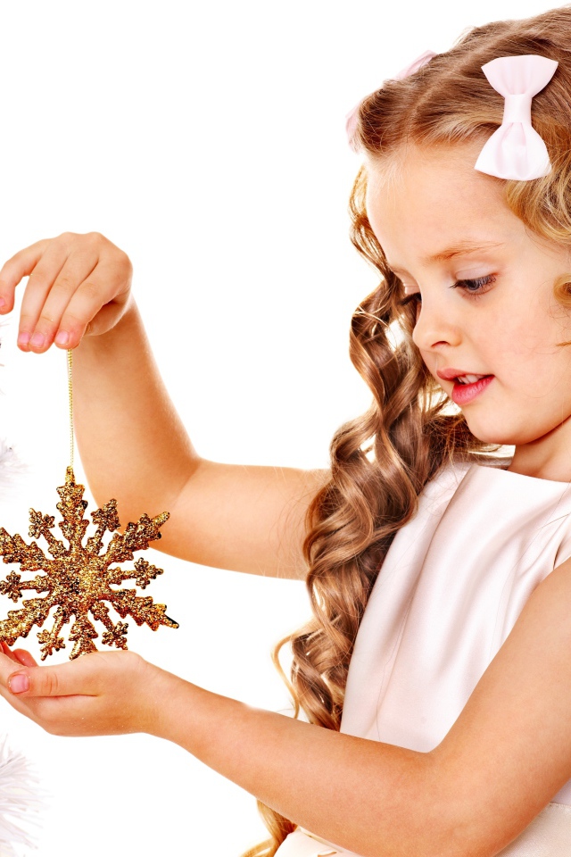 Маленькая девочка держит елочную игрушку снежинку в руке