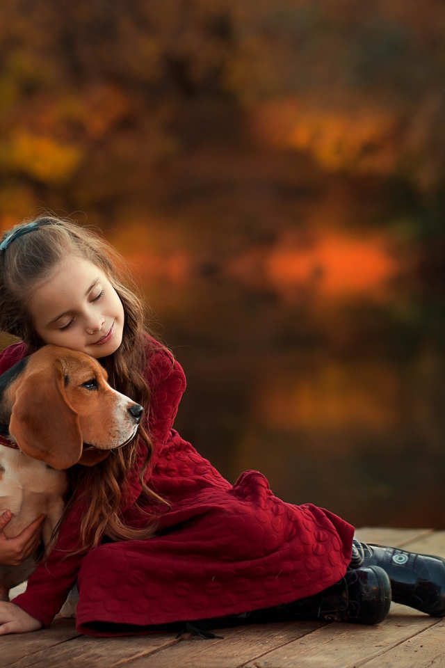 Маленькая девочка обнимает собаку породы бигль на мосту