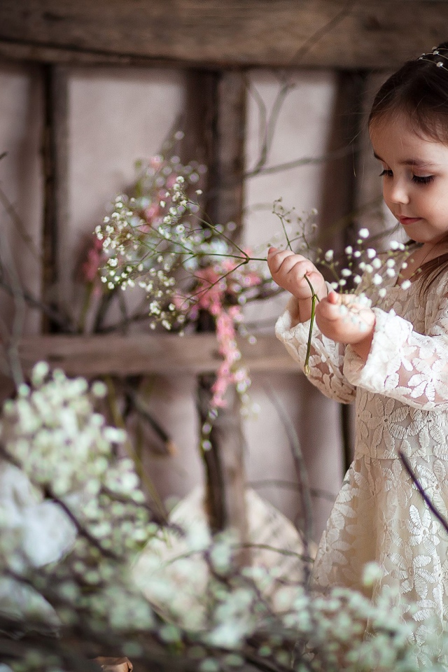 Маленькая девочка в красивом платье с белыми цветами в руке