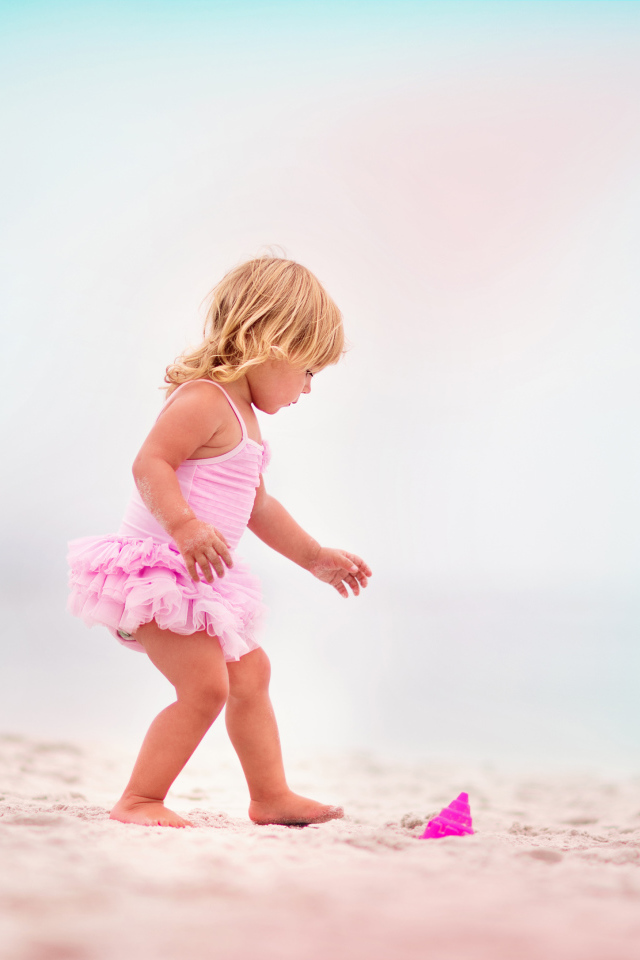 Маленькая девочка в розовом купальнике на песке