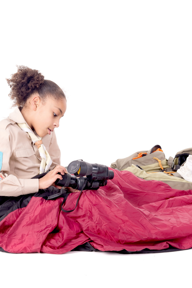 Маленькая девочка в спальном мешке с биноклем