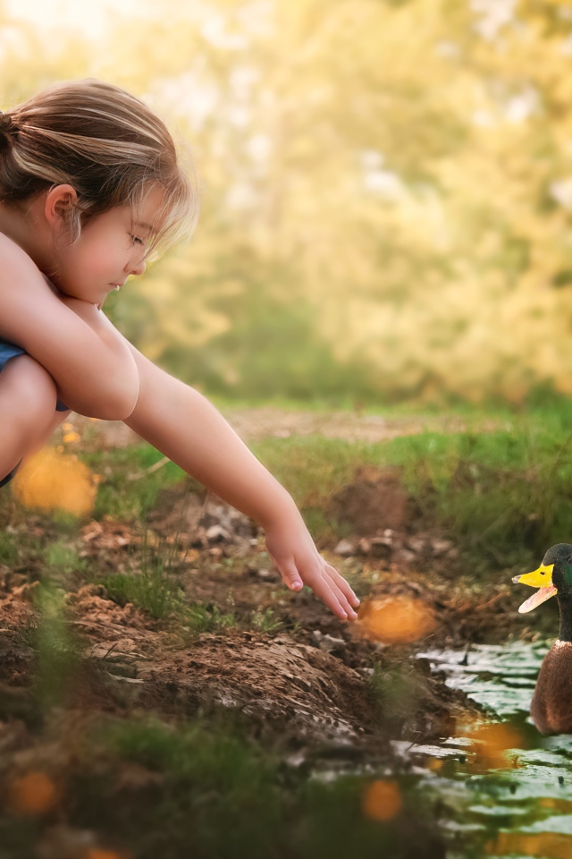 Маленькая девочка играет с уточкой в воде