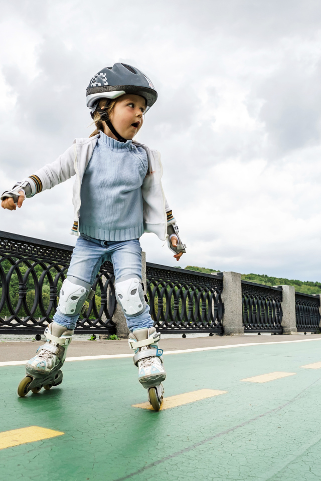 Маленькая девочка катается по мосту на роликах