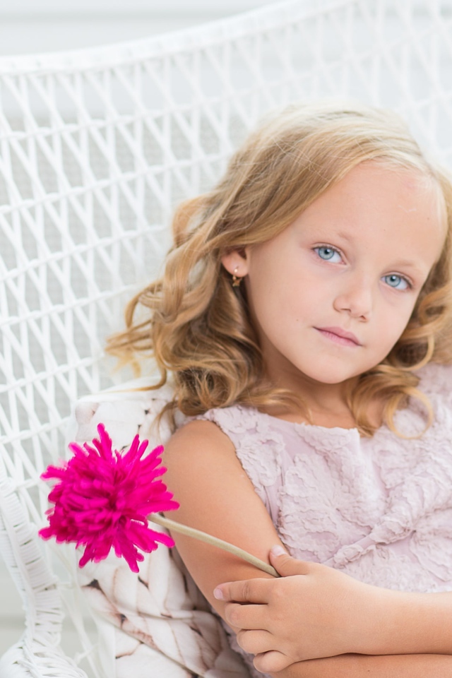 Маленькая девочка сидит в белом кресле с розовым цветком