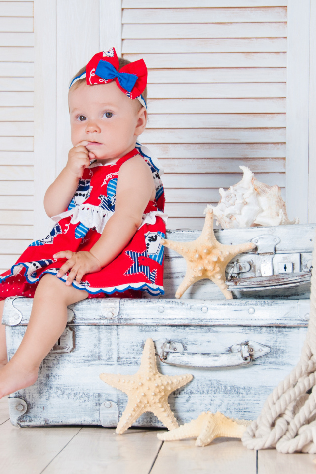 Маленькая девочка сидит на чемодане с морскими звездами