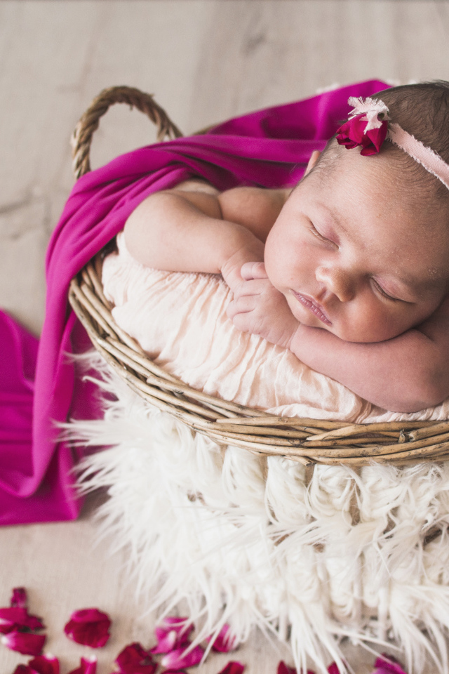 Маленькая девочка спит в корзине под покрывалом