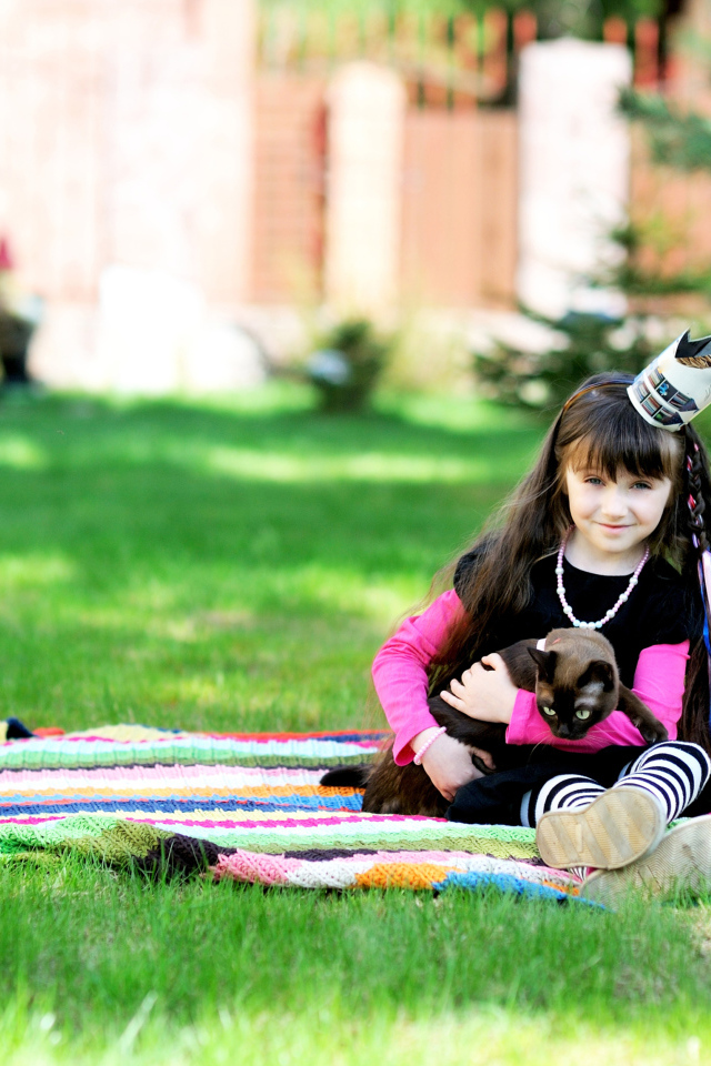 Маленькая девочка с котом сидит на зеленой траве