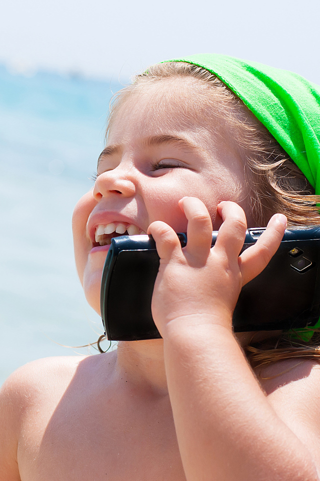 Маленькая девочка с телефоном на пляже