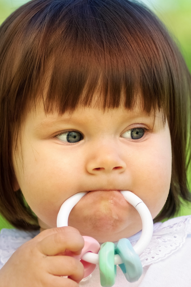 Маленькая девочка с погремушкой во рту