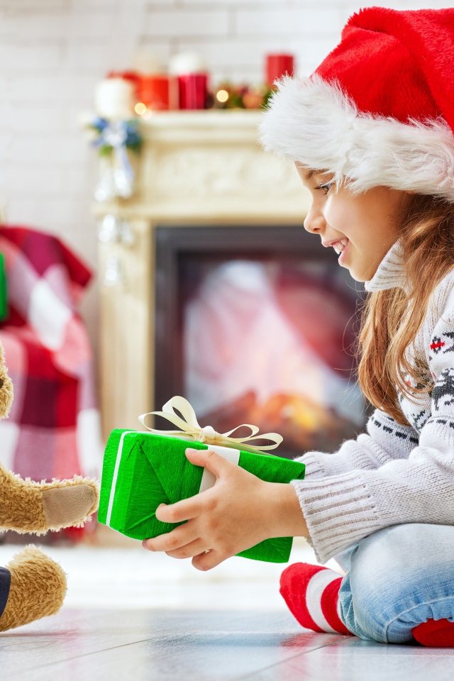 Маленькая девочка с медвежонком Тедди у елки с подарками на Новый год