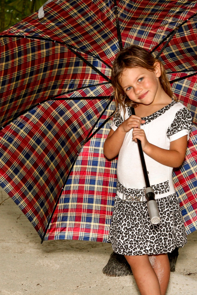 Маленькая девочка с большим зонтом на пляже