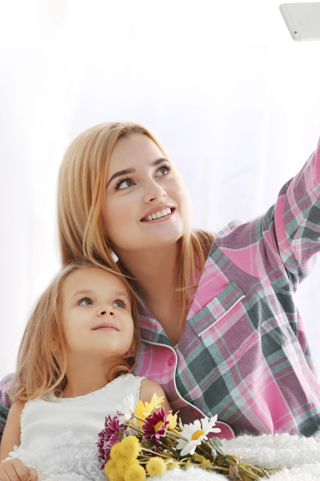 Маленькая девочка с мамой делают фото на смартфон