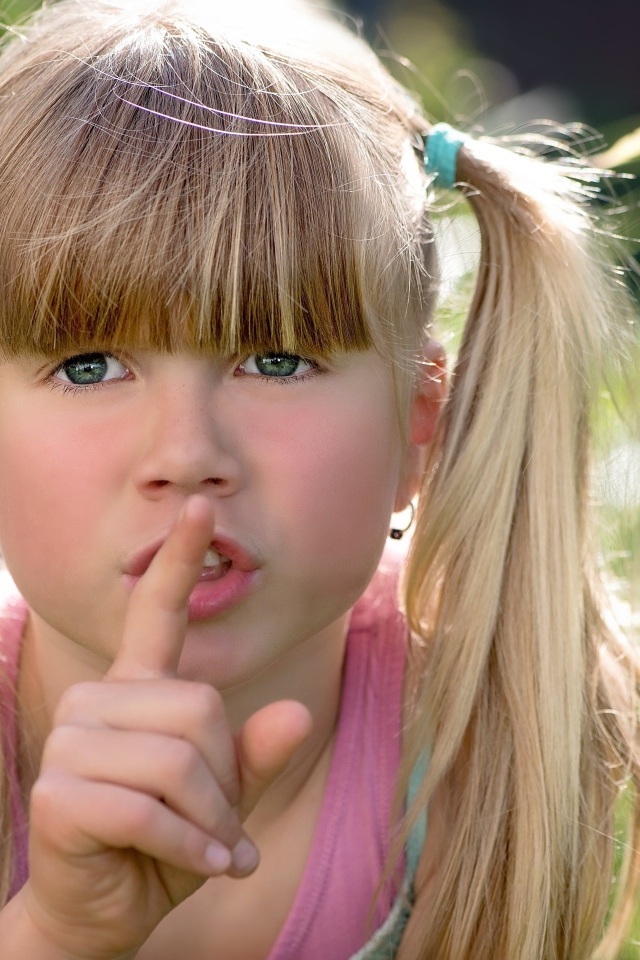 Маленькая зеленоглазая девочка с пальцем у рта 