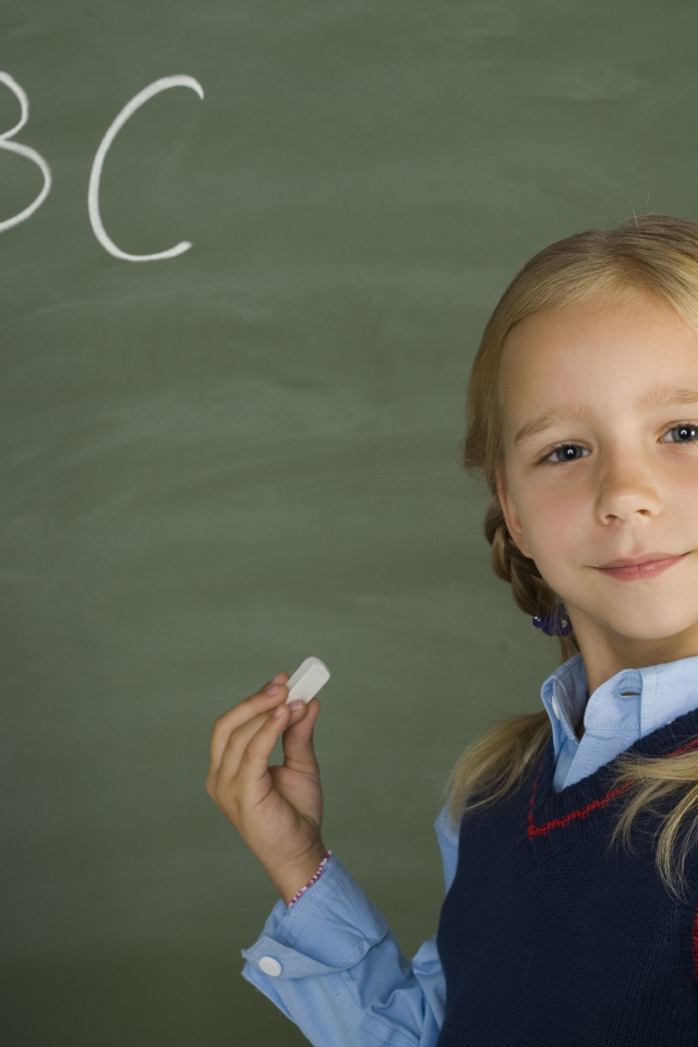 Маленькая школьница пишет буквы на доске 