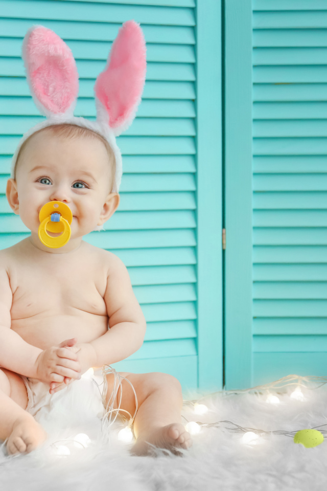 Маленький улыбающийся малыш с ушками зайчика на голове