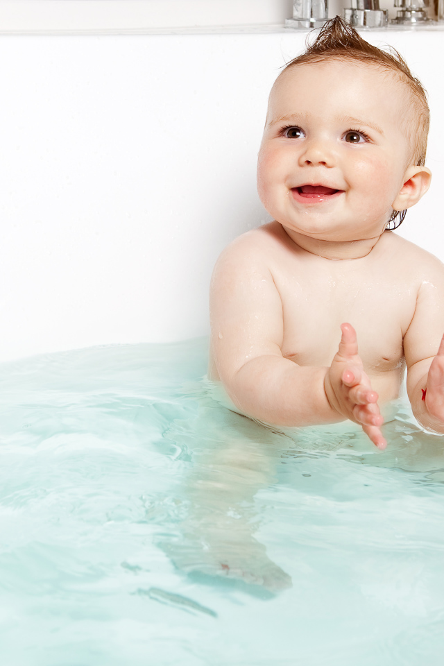 Маленький улыбающийся ребенок с игрушками в ванной 