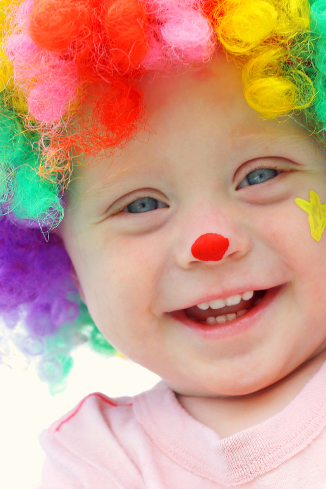 Маленький улыбающийся мальчик в костюме клоуна на белом фоне