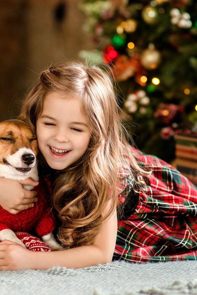 Веселая девочка с собакой у елки 