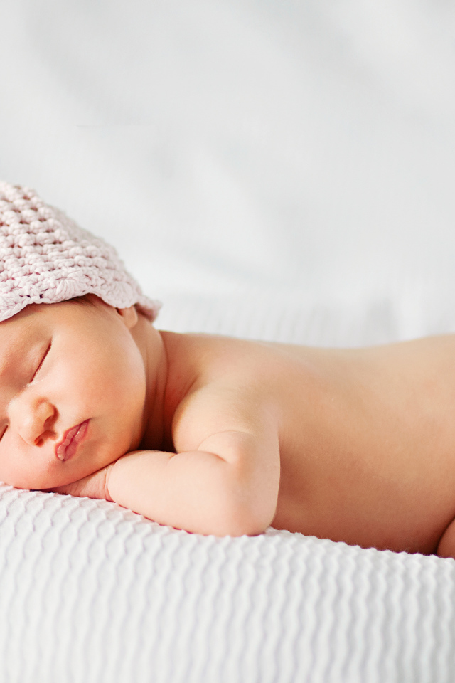 Спящий грудной ребенок девочка на белом покрывале